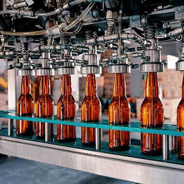 Glasflaschen auf ihrem Weg durch eine Getränkeproduktionsanlage. Die Überwachung der Wasserhärte ist wichtig für die Eihaltung der Produktqualität.